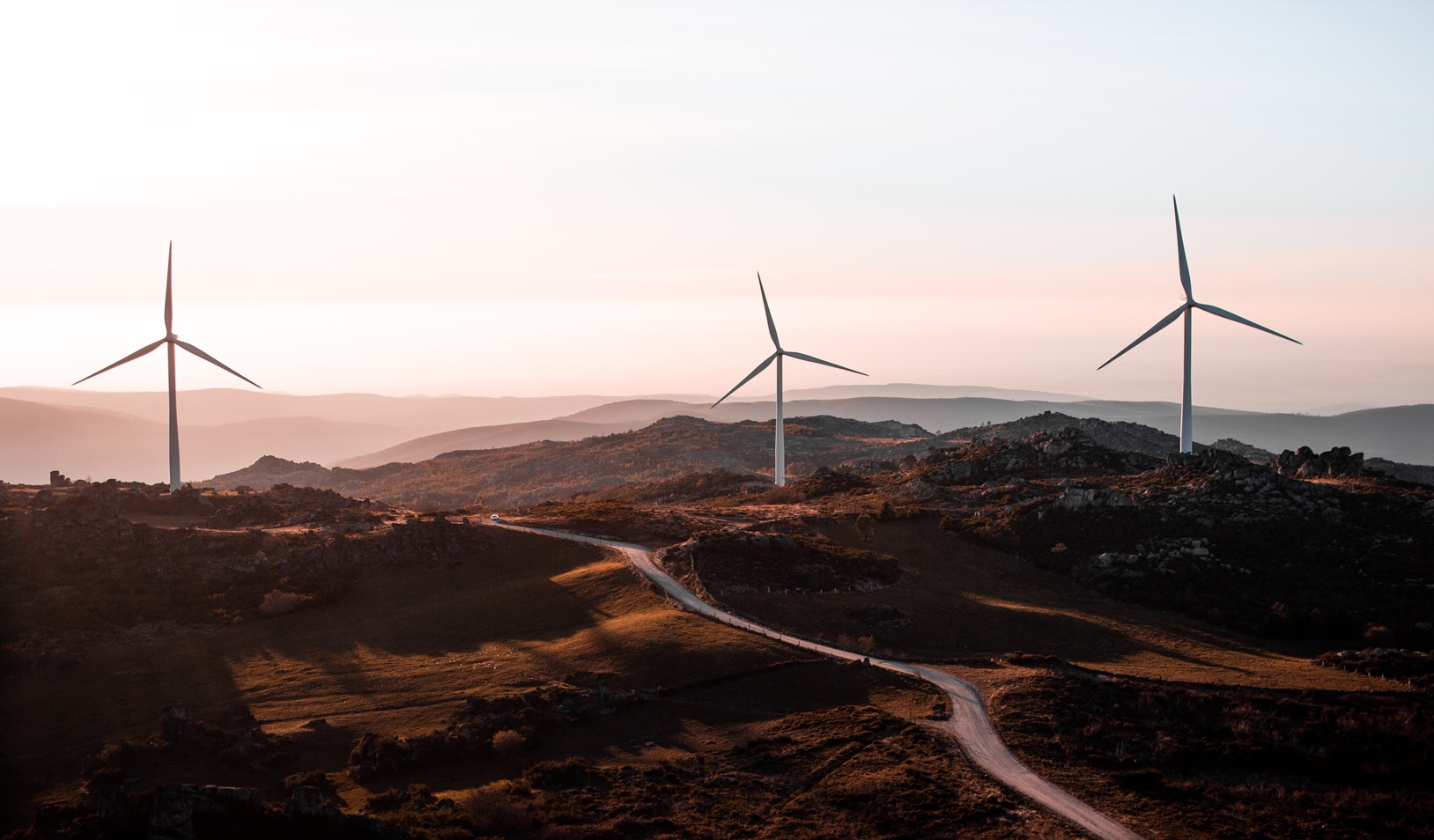 wind turbines on a hilly landscape at sunset, representing renewable energy and the energy transition